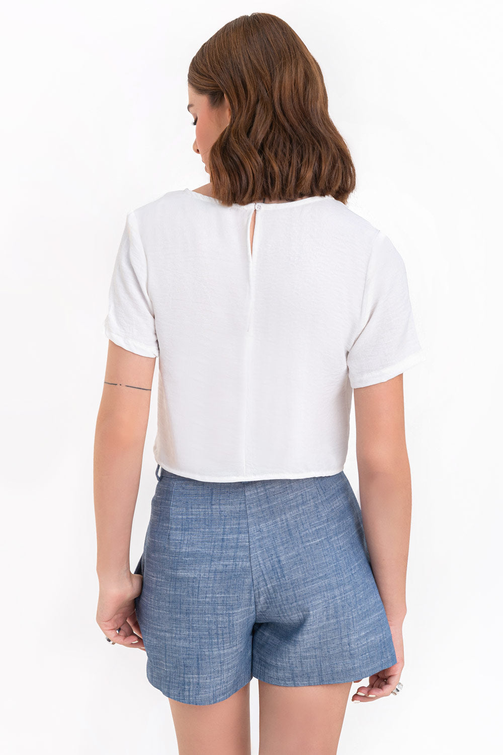 Blusa corta de fit ligeramente oversized, de cuello redondo, manga corta y cierre posterior con botón y ojal.