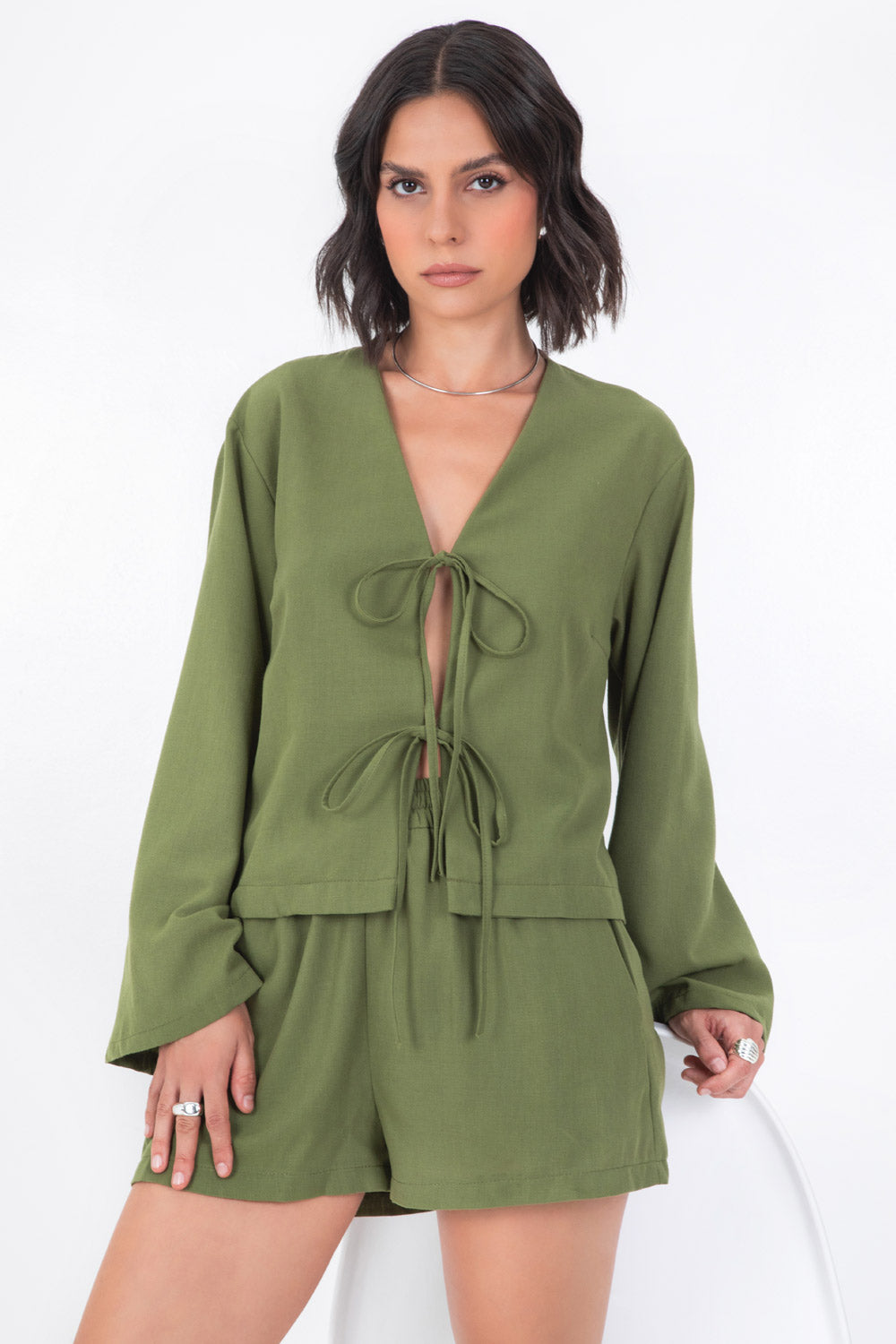 Blusa corta de fit recto, manga larga de puño amplio, escote v y cierre frontal con lazado amarrable.