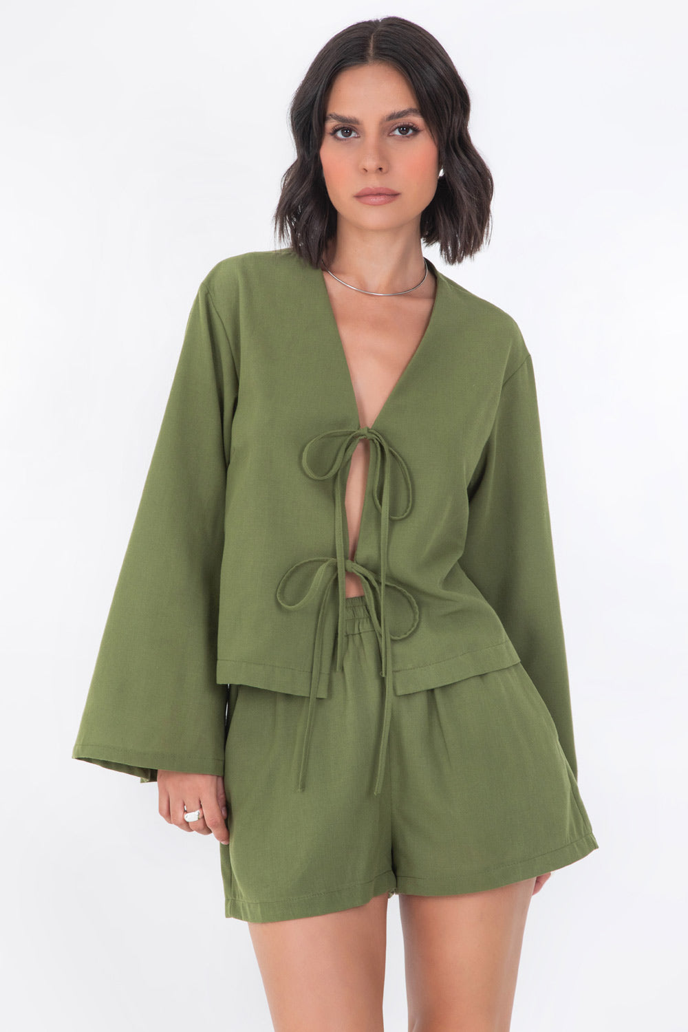 Blusa corta de fit recto, manga larga de puño amplio, escote v y cierre frontal con lazado amarrable.