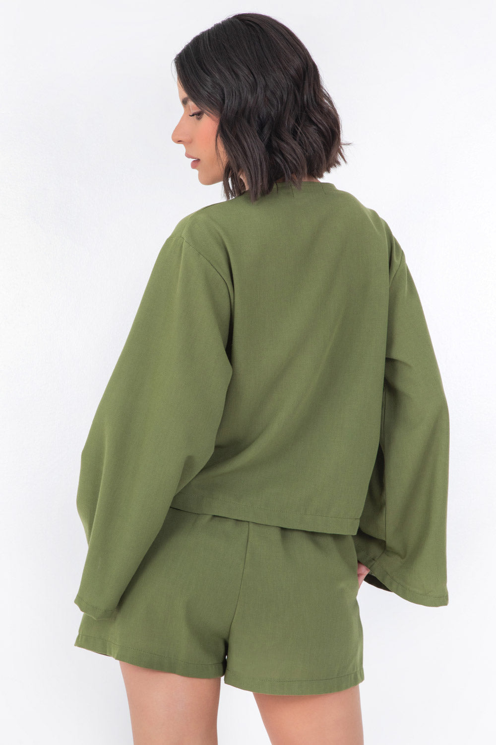 Blusa corta de fit recto, manga larga de puño amplio, escote v y cierre frontal con lazado amarrable.