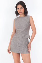 Blusa corta ajustada de estampado rayas, sin mangas, cuello redondo, corte en a, pinzas frontales y cut out en espalda con lazo amarrable posterior. Cierre posterior con botón y ojal.