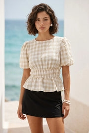 Blusa de estampado cuadros, manga corta abullonada con plisados en hombros, cuello redondo, rib elástico en cintura y peplum con olanes en bajo. Cierre posterior con botón y ojal.