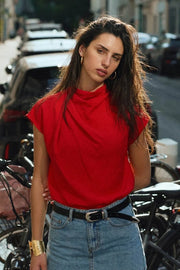 Blusa fluida de manga corta seguida, cuello mock seguido con plisados decorativos en hombro y cuello. Cierre posterior con botones y ojales.