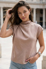 Blusa fluida de manga corta seguida, cuello mock seguido con plisados decorativos en hombro y cuello. Cierre posterior con botones y ojales.
