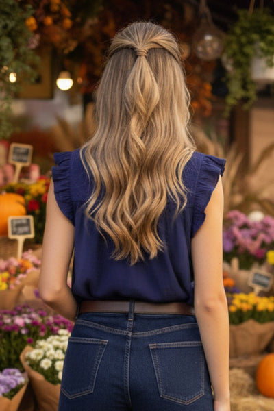 Blusa de fit recto, cuello redondo, sin mangas, olanes en sisa y costuras decorativas frontales con plisados. Cierre posterior con botón y ojal.