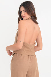 Blusa fluida de cuello alto halter con plisados, sin mangas, escote en espalda y bajo frontal asimétrico. Cierre posterior con broches.