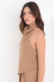 Blusa fluida de cuello alto halter con plisados, sin mangas, escote en espalda y bajo frontal asimétrico. Cierre posterior con broches.