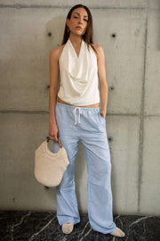 Blusa de cuello halter, escote fluido frontal, sin mangas y escote en espalda.