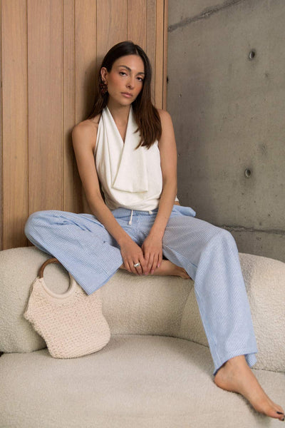 Blusa de cuello halter, escote fluido frontal, sin mangas y escote en espalda.