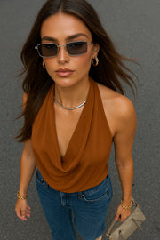 Blusa de cuello halter, escote fluido frontal, sin mangas y escote en espalda.