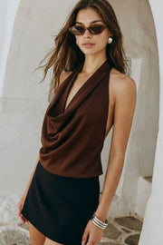 Blusa de cuello halter, escote fluido frontal, sin mangas y escote en espalda.