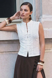 Blusa de fit ajustado, sin mangas, cuello mao, cut out frontal con hilera de botones y detalle de textura en tejido. Detalle de encaje decorativo.