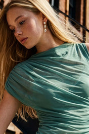 Blusa de mesh, fit ajustado, plisados en costado y hombros, cuello mock seguido, detalle decorativo de capa con plisados y manga corta seguida.