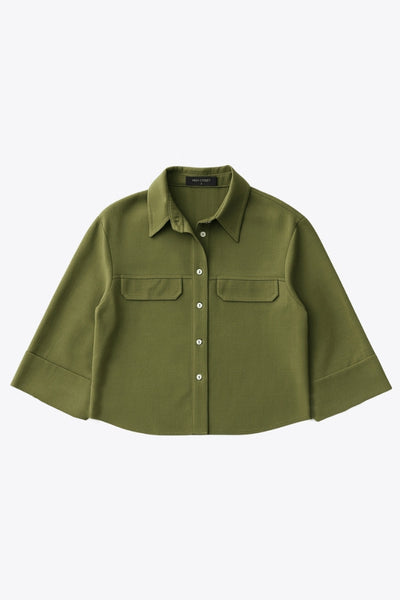 Camisa corta de fit oversized, manga 3/4 amplia con doblez en puños, cuello camisero, bolsillos frontales decorativos con cartera y pinza de amplitud en espalda. Cierre frontal con hilera de botones.