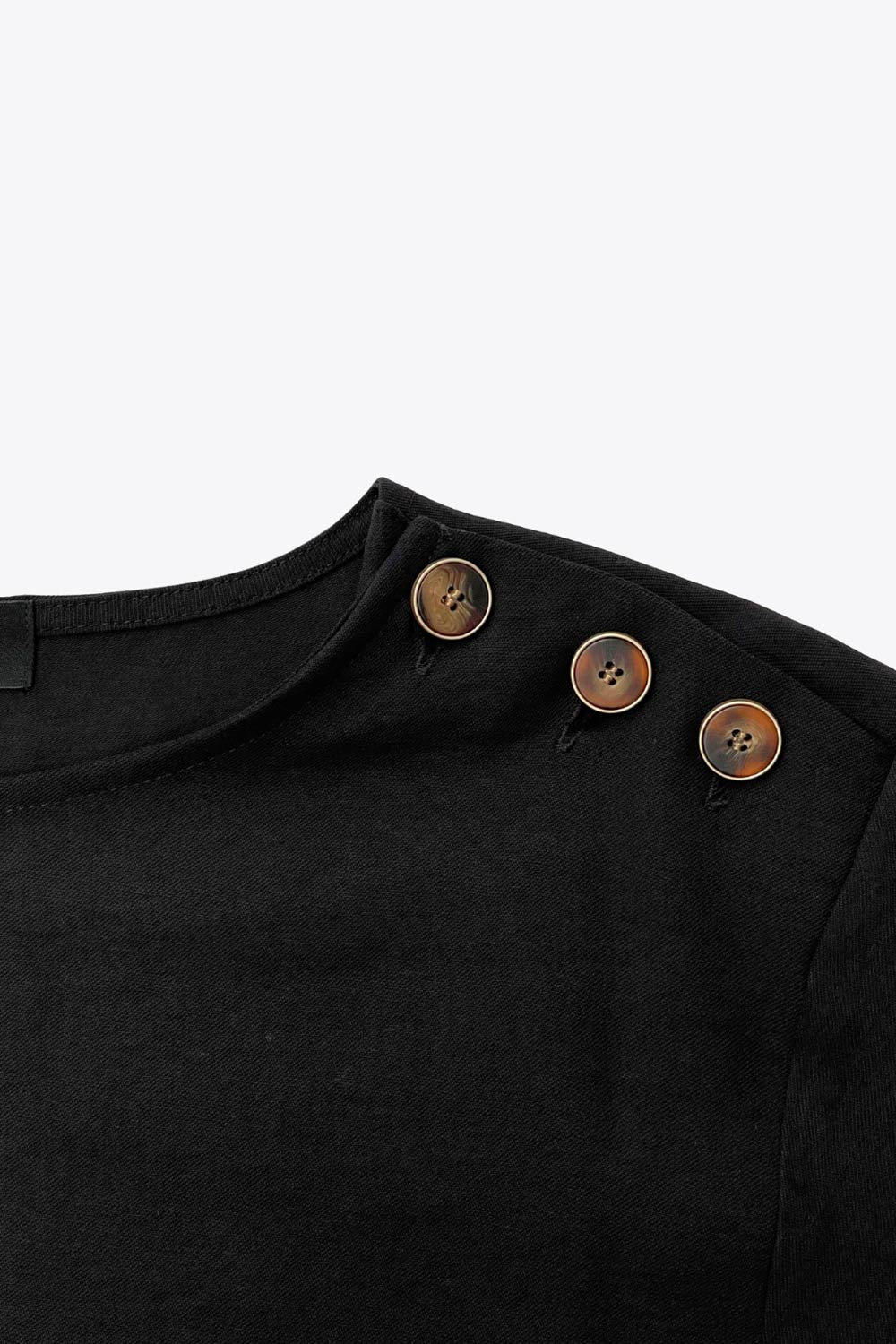 Blusa amplia de fit fluido, cuello redondo, manga larga con hombro caído y botones decorativos en hombro.