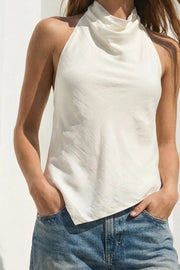 Blusa asimétrica de fit fluido, sin mangas, cuello halter fluido con plisados, escote en espalda y lazo amarrable posterior. Cierre posterior con botón y ojal. Detalle de bajo frontal asimétrico.