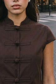 Blusa corta de fit recto, cuello mao, manga corta y cierre frontal con botones alamares.