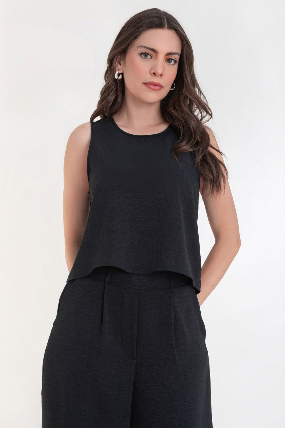 Blusa sin mangas de fit ligeramente oversized, cuello redondo y cierre posterior con botón y ojal.