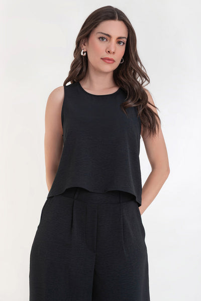 Blusa sin mangas de fit ligeramente oversized, cuello redondo y cierre posterior con botón y ojal.