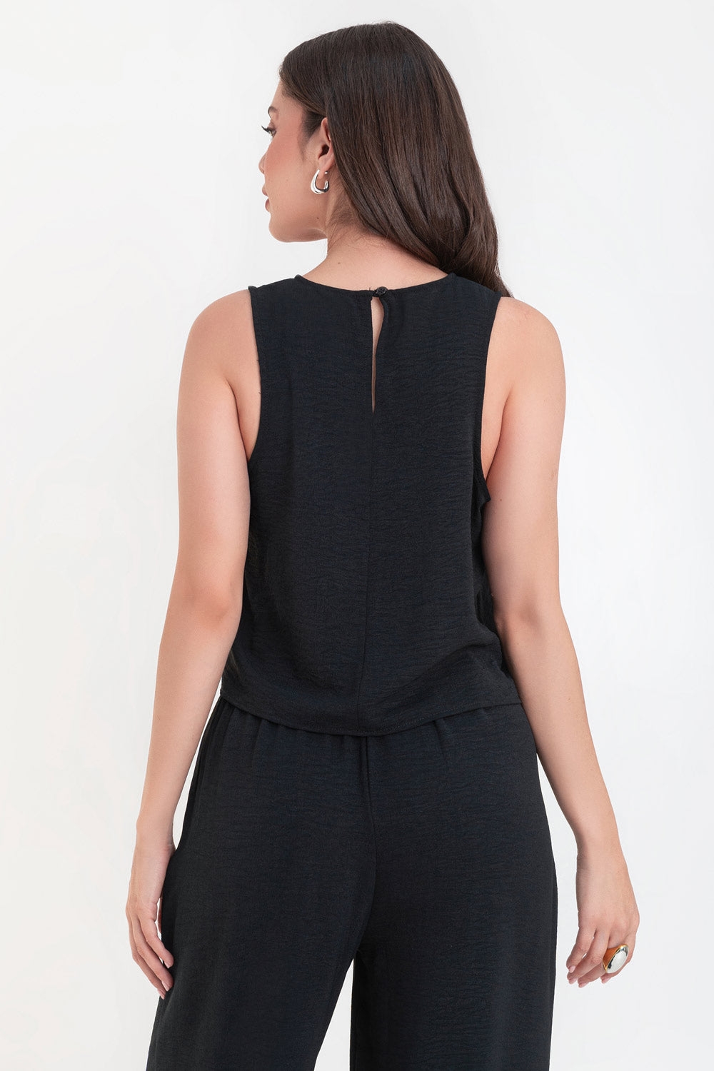 Blusa sin mangas de fit ligeramente oversized, cuello redondo y cierre posterior con botón y ojal.