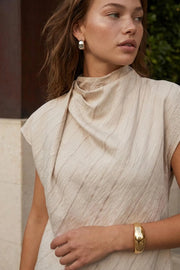 Blusa de estampado rayas, cuello alto fluido, plisados en hombros, manga corta seguida y fit recto. Cierre posterior con botón y ojal.