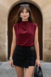 Blusa de fit oversized, sin mangas y cuello alto con detalles plisados en hombros.