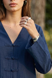 Blusa de manga larga, fit recto, escote v y cierre frontal con botones alamares.