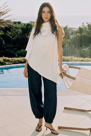 Blusa túnica asimétrica de una manga corta seguida con olanes, cuello mock seguido, bajo asimétrico y cierre posterior con botón y ojal.