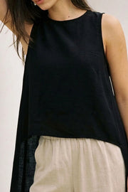 Blusa túnica sin mangas, cuello redondo, bajo frontal asimétrico, corte en a, cierre posterior con botón y ojal. Detalle de plisados en hombros.