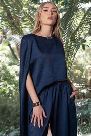 Blusa tipo túnica asimétrica, de cuello redondo, con hombreras, una manga corta seguida, fit fluido y bajo asimétrico.