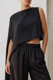 Blusa tipo túnica asimétrica, de cuello redondo, con hombreras, una manga corta seguida, fit fluido y bajo asimétrico.