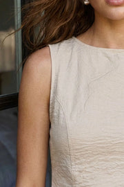 Blusa corta de fit ajustado, cuello redondo, sin mangas, pinzas frontales y cut out en espalda con lazo amarrable posterior. Cierre con botón y ojal posterior.