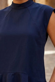 Blusa larga de fit fluido, manga corta seguida con cortes, cuello mock, corte en cadera y peplum con olanes en bajo. Cierre posterior con cremallera oculta.