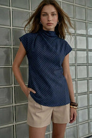 Blusa de estampado rayas, cuello alto fluido, plisados en hombros, manga corta seguida y fit recto. Cierre posterior con botón y ojal.