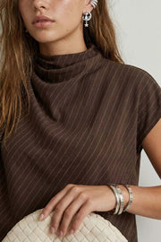 Blusa de estampado rayas, cuello alto fluido, plisados en hombros, manga corta seguida y fit recto. Cierre posterior con botón y ojal.
