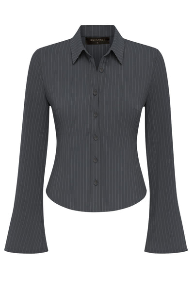 Camisa ajustada de estampado rayas, cuello camisero, manga larga con amplitud y abertura en puños. Cierre frontal con hilera de botones.