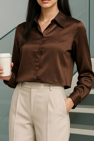 Camisa corta satinada de fit recto, cuello camisero, manga larga con puño abotonado, pinza de amplitud en espalda y cierre frontal con hilera de botones.
