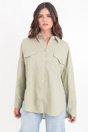 Camisa de lino, fit oversized, cuello camisero, manga larga con puño abotonado y trabillas ajustables, bolsillos frontales de parche con cartera y bajo curveado. Cierre frontal con hilera de botones.