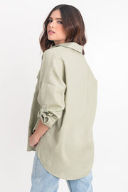 Camisa de lino, fit oversized, cuello camisero, manga larga con puño abotonado y trabillas ajustables, bolsillos frontales de parche con cartera y bajo curveado. Cierre frontal con hilera de botones.