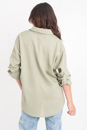 Camisa de lino, fit oversized, cuello camisero, manga larga con puño abotonado y trabillas ajustables, bolsillos frontales de parche con cartera y bajo curveado. Cierre frontal con hilera de botones.