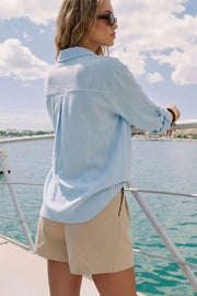 Camisa corta de fit recto, manga larga rolled up con trabilla ajustable, cuello camisero, cruce frontal con escote v y nudo decorativo en bajo. Detalle de bajo curveado y pinza de amplitud en espalda.