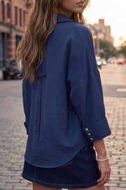 Camisa de fit oversized, manga 3/4 amplia con doblez en puños, cuello camisero, escote v, pinza de amplitud en espalda con trabilla decorativa y bajo curveado. Cierre frontal con hilera de botones en contraste.