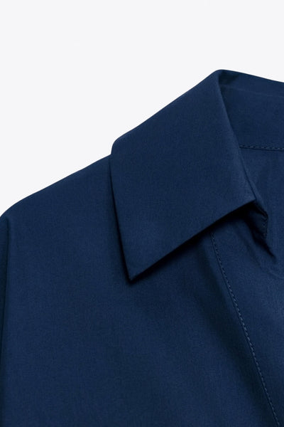 Camisa de fit oversized, manga 3/4 amplia con doblez en puños, cuello camisero, escote v, pinza de amplitud en espalda con trabilla decorativa y bajo curveado. Cierre frontal con hilera de botones en contraste.