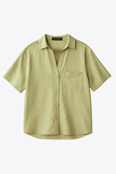 Camisa corta de lino, fit recto, manga corta, cuello camisero, bolsillo frontal de parche, bajo curveado con aberturas laterales y cierre frontal con hilera de botones.