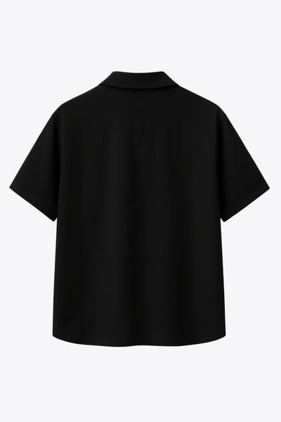 Camisa corta de lino, fit recto, manga corta, cuello camisero, bolsillo frontal de parche, bajo curveado con aberturas laterales y cierre frontal con hilera de botones.