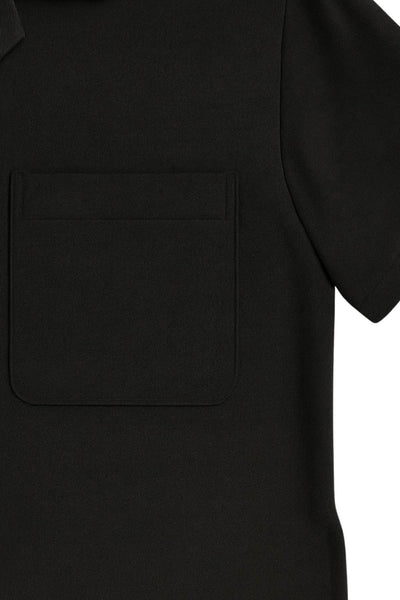 Camisa corta de lino, fit recto, manga corta, cuello camisero, bolsillo frontal de parche, bajo curveado con aberturas laterales y cierre frontal con hilera de botones.