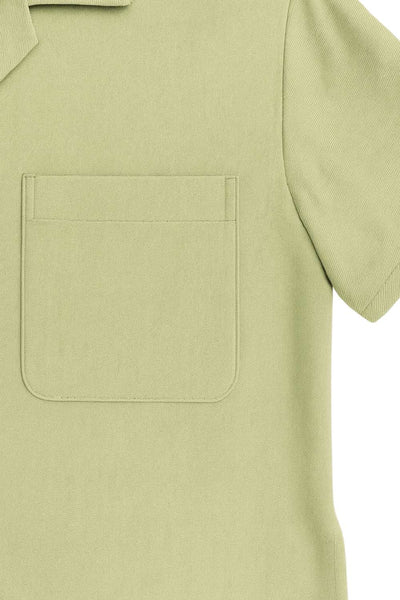 Camisa corta de lino, fit recto, manga corta, cuello camisero, bolsillo frontal de parche, bajo curveado con aberturas laterales y cierre frontal con hilera de botones.