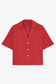 Camisa corta de fluido, manga corta de hombro caído, fruncido decorativo posterior con plisados, cuello camisero, escote v y cierre frontal con hilera de botones en contraste.