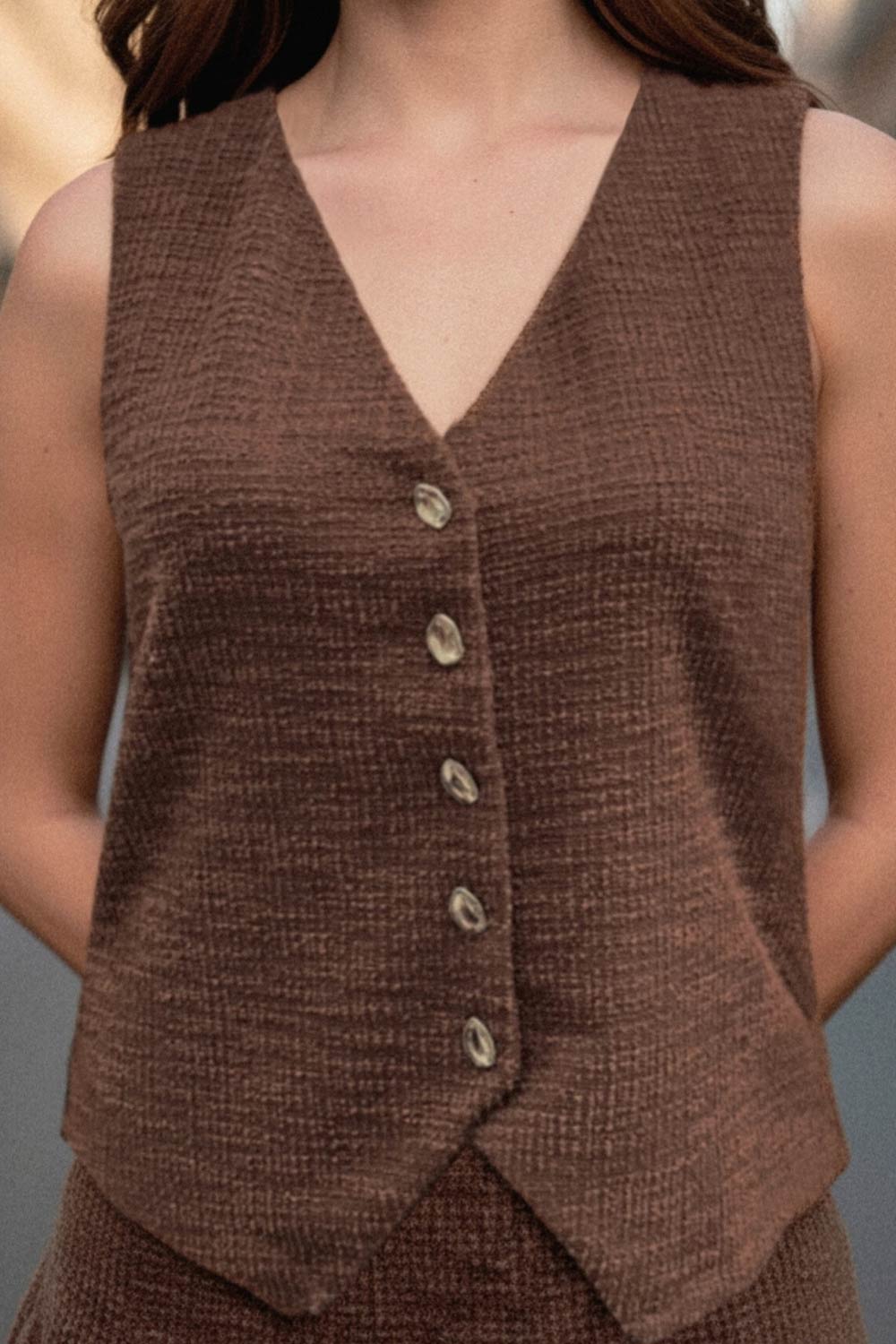 Chaleco de bouclé, fit recto, escote v, cierre con hilera de botones en contraste y abertura frontal v en bajo.