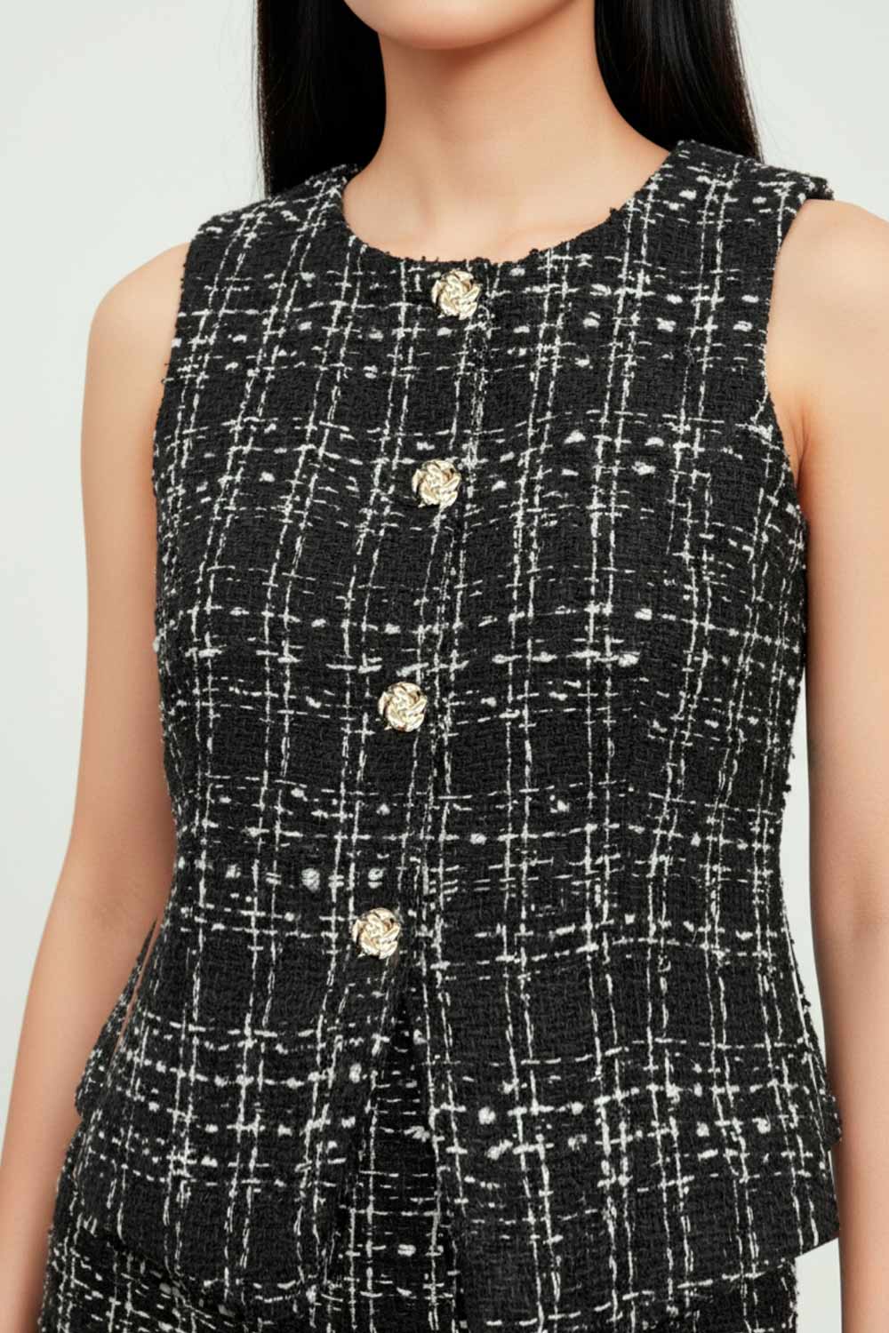 Chaleco de bouclé fit ajustado, cuello redondo, vivos decorativos frontales, cierre con hilera de botones en contraste y abertura frontal en bajo.